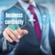 man in a suit shown from the shoulders down selects a floating icon with the words "business continuity"