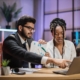 two coworkers in office working on computer with managed IT services