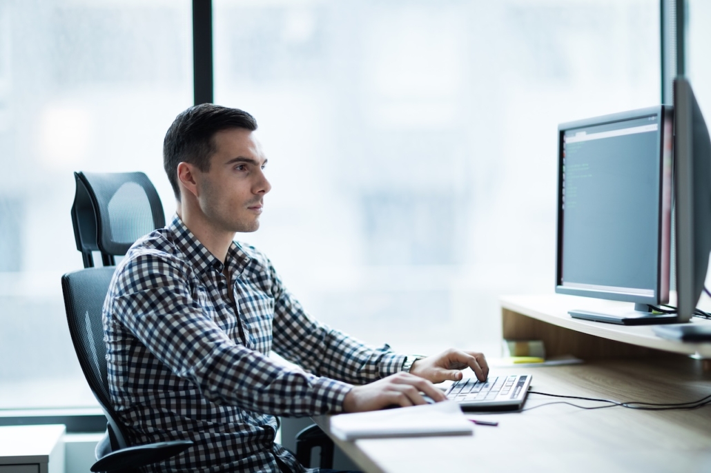 man working on computer in office avoiding network vulnerabilities with IT support
