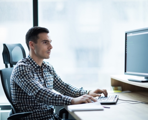 man working on computer in office avoiding network vulnerabilities with IT support