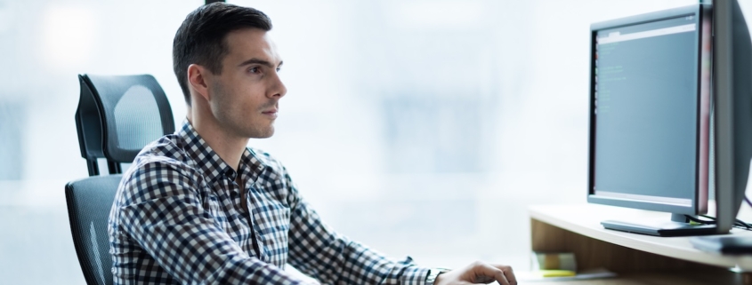man working on computer in office avoiding network vulnerabilities with IT support