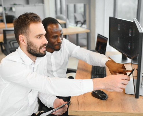 men working in office on computer looking at monitor