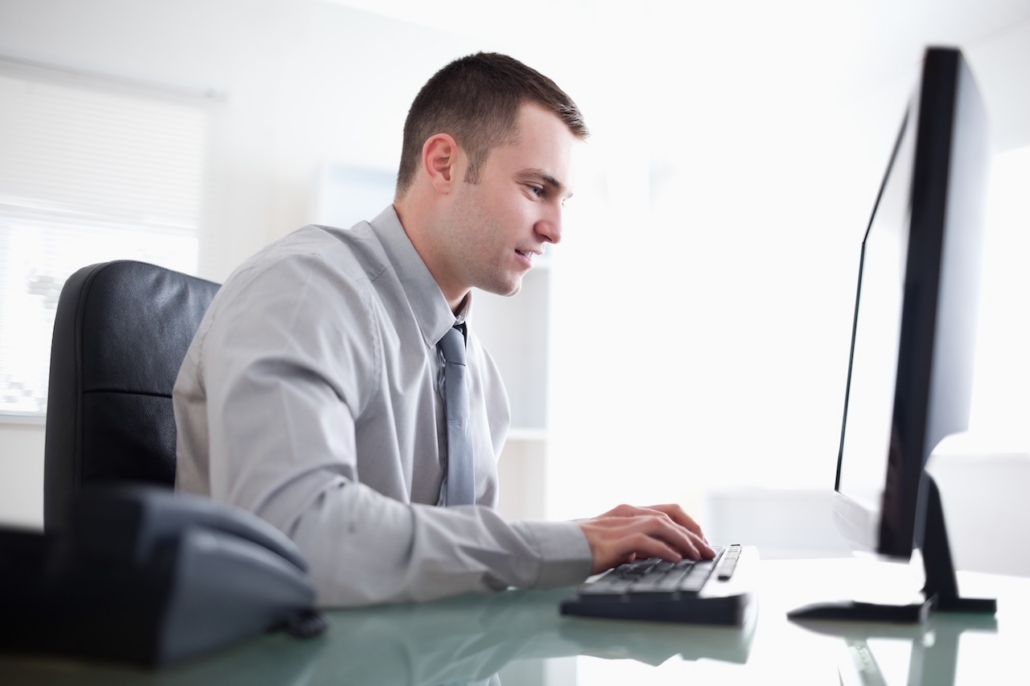 man working on computer in brightly lit officer