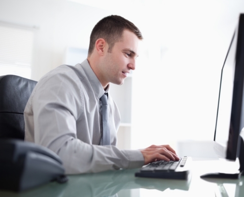 man working on computer in brightly lit officer