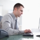 man working on computer in brightly lit officer