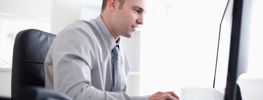 man working on computer in brightly lit officer